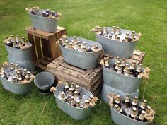 a bunch of buckets that are sitting in the grass next to some beer bottles