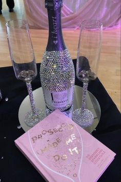 a bottle of champagne and two wine glasses on a table with pink napkins in front of it