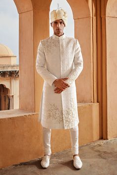 a man standing in front of a building wearing a white outfit