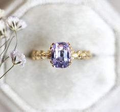 a tan and purple ring sitting on top of a white surface next to some flowers