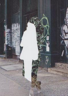 a person walking down the street in front of some graffiti covered buildings and doors,