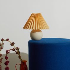 a table lamp sitting on top of a blue cake next to a vase with flowers