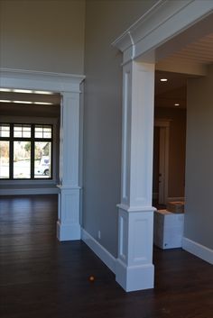 an empty room with wood floors and white columns