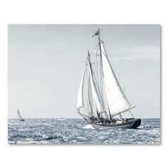 a sailboat sailing in the ocean on a sunny day with another boat behind it