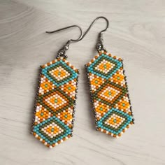 two pairs of beaded earrings sitting on top of a table