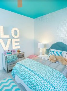 a bedroom decorated in blue and white with the word love spelled on the wall above the bed