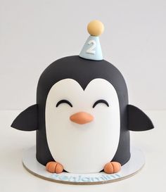 a birthday cake with a penguin on it's head and number two on top