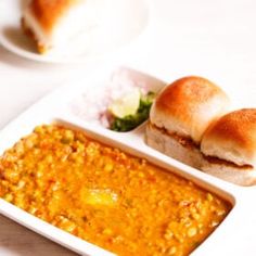 a white plate topped with two rolls next to a bowl of soup