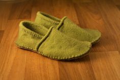 a pair of green slippers sitting on top of a wooden floor