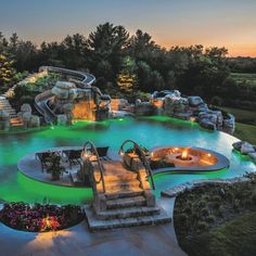 an outdoor swimming pool at dusk with steps leading up to the water slide and waterfall