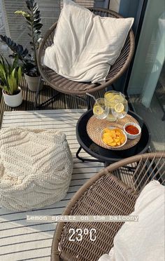 two wicker chairs sitting next to each other on top of a patio with food