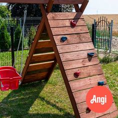 a wooden climbing frame with an orange sign that says anggi above it and a red bucket in the foreground