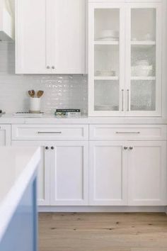 a kitchen with white cabinets and wood floors