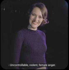 a woman wearing a purple sweater smiles at the camera with an uncontrollable, violent, female anger message