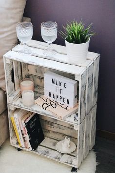 a shelf with some books and glasses on top of it next to a white couch