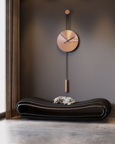 a dog laying on top of a black couch in front of a wall mounted clock