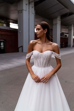 a woman in a wedding dress standing on the street