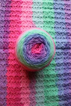 a ball of yarn sitting on top of a colorful striped blanket next to a crochet hook