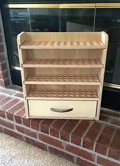 a wooden shelf sitting on top of a brick floor next to a window sill