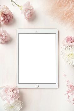 an ipad sitting on top of a table next to pink flowers