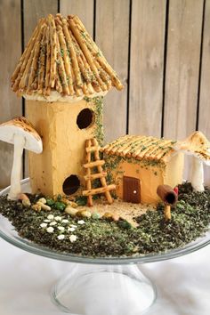 a cake that looks like a house with mushrooms on the roof and in the ground