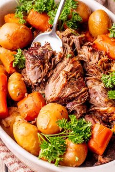 a bowl filled with meat, potatoes and carrots on top of a table cloth