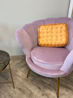 a purple chair with a pillow on it next to a small table and stools