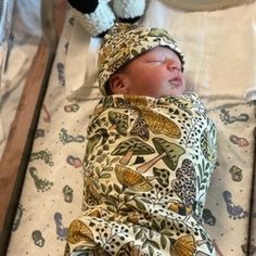 a baby wrapped in a blanket sleeping next to a stuffed animal