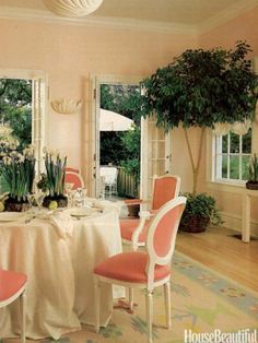 the dining room is decorated with pink chairs and white table cloths, along with potted plants