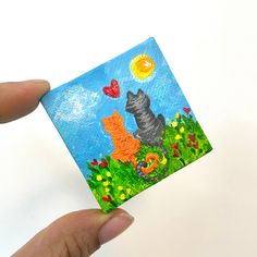 a hand holding up a small card with a dog and cat on it