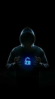 a man in a hoodie is holding a glowing blue light up computer key on his chest