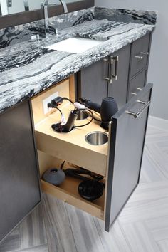 an open cabinet in the middle of a bathroom with sink and hair dryer on it