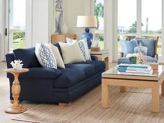 a living room with blue couches and coffee table in front of large windows overlooking the ocean