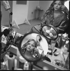 a girl is looking in the mirror while brushing her hair