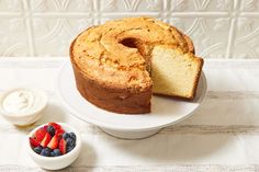 a bundt cake with one slice cut out on a plate next to berries and yogurt