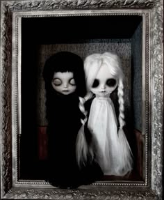 two dolls dressed in black and white are posed for a photo with their eyes closed