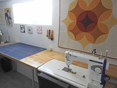 a sewing machine sitting on top of a wooden table in front of a wall with pictures