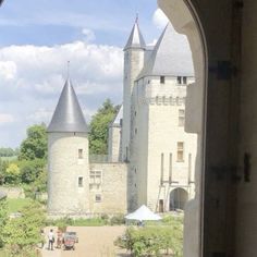 an old castle with two towers is seen through a window that looks out onto the grounds