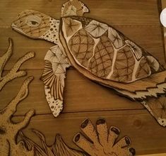 a wood carving of a sea turtle and corals on a wooden table with paper cutouts