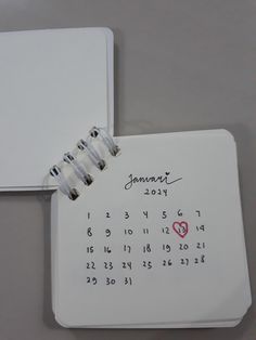 a calendar with a heart on it next to a notepad