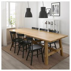 a dining room table with black chairs and pictures on the wall in the back ground