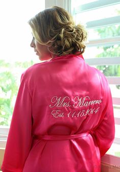 a woman in a pink robe looking out the window with her name written on it