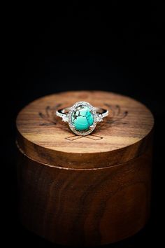 an engagement ring with a turquoise stone in the center on top of a wooden box