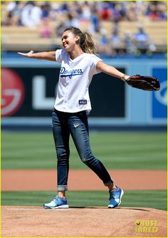 a woman throwing a baseball on top of a field