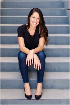 a woman sitting on the steps in front of some stairs with her legs crossed and smiling