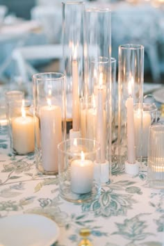 Colored pillar and taper candle centerpiece with blue print linen. Stem Candles Wedding, Candle Focused Wedding Centerpiece, Candle Trio Centerpiece, Nonfloral Centerpiece Ideas, Taper Candle Centerpieces, Candle Centerpiece Wedding, Taper Candle Centerpiece, Timeless White Wedding, Light Blue Wedding Theme