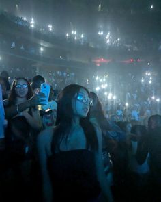 a group of people standing in front of a crowd at a concert with their cell phones