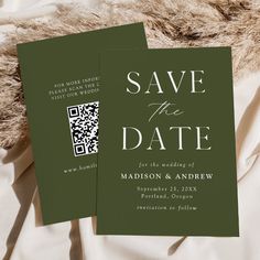 two green save the dates cards sitting on top of a white bed sheet with fur