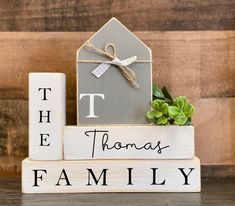 a wooden block that says the thomas family with a house on it and a potted plant