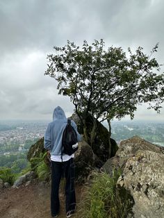 a person standing on top of a hill next to a tree